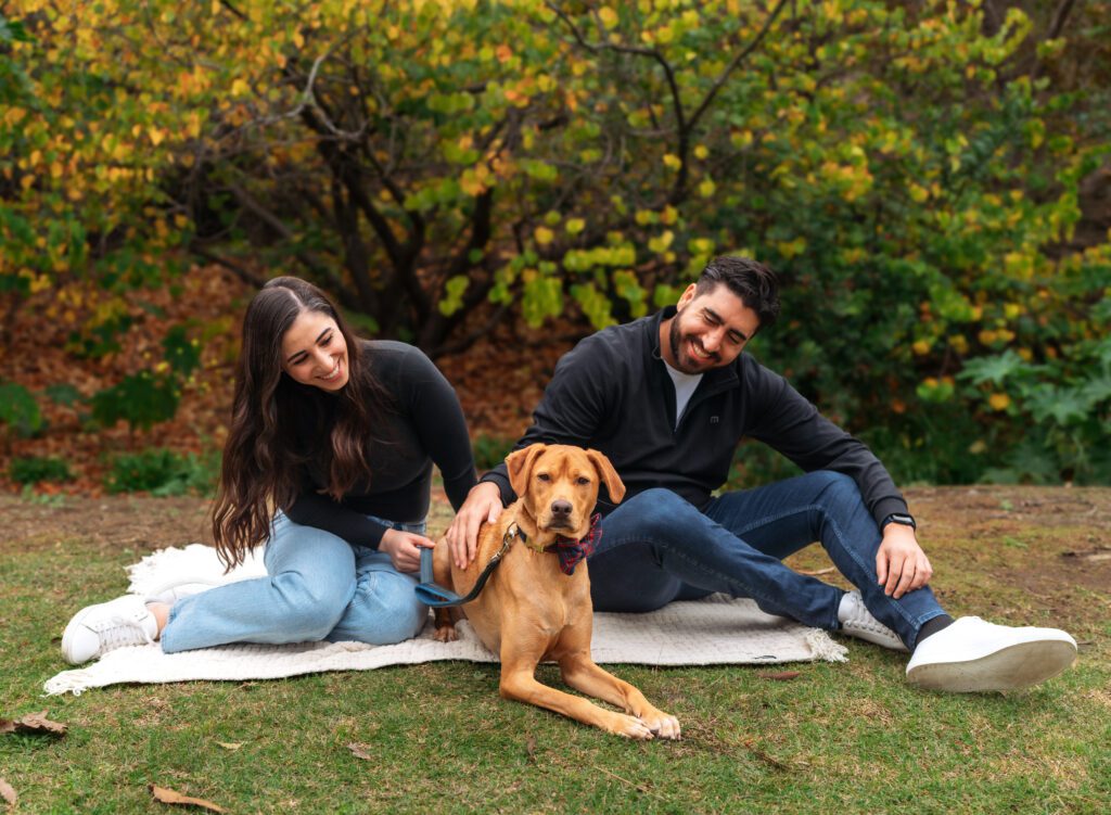 A couple and their dog sitting on a picnic blanket taking family photos in Los Angeles