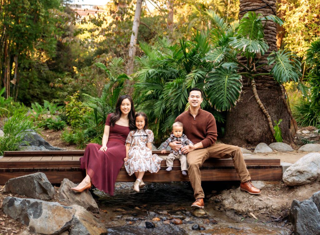 family of four sitting on a log taking family photos in Los Angeles