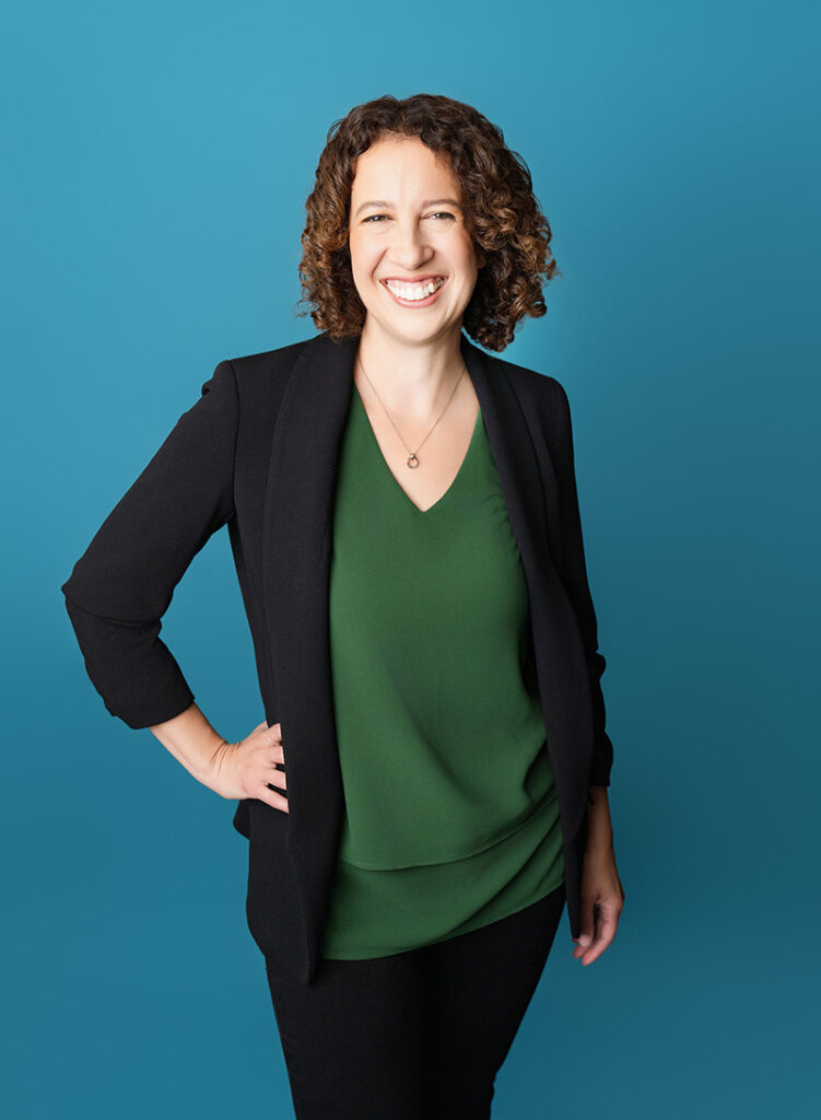 Headshots of a young female in a black cardigan and green shirt against a blue backdrop with Emily Winnie Photography.